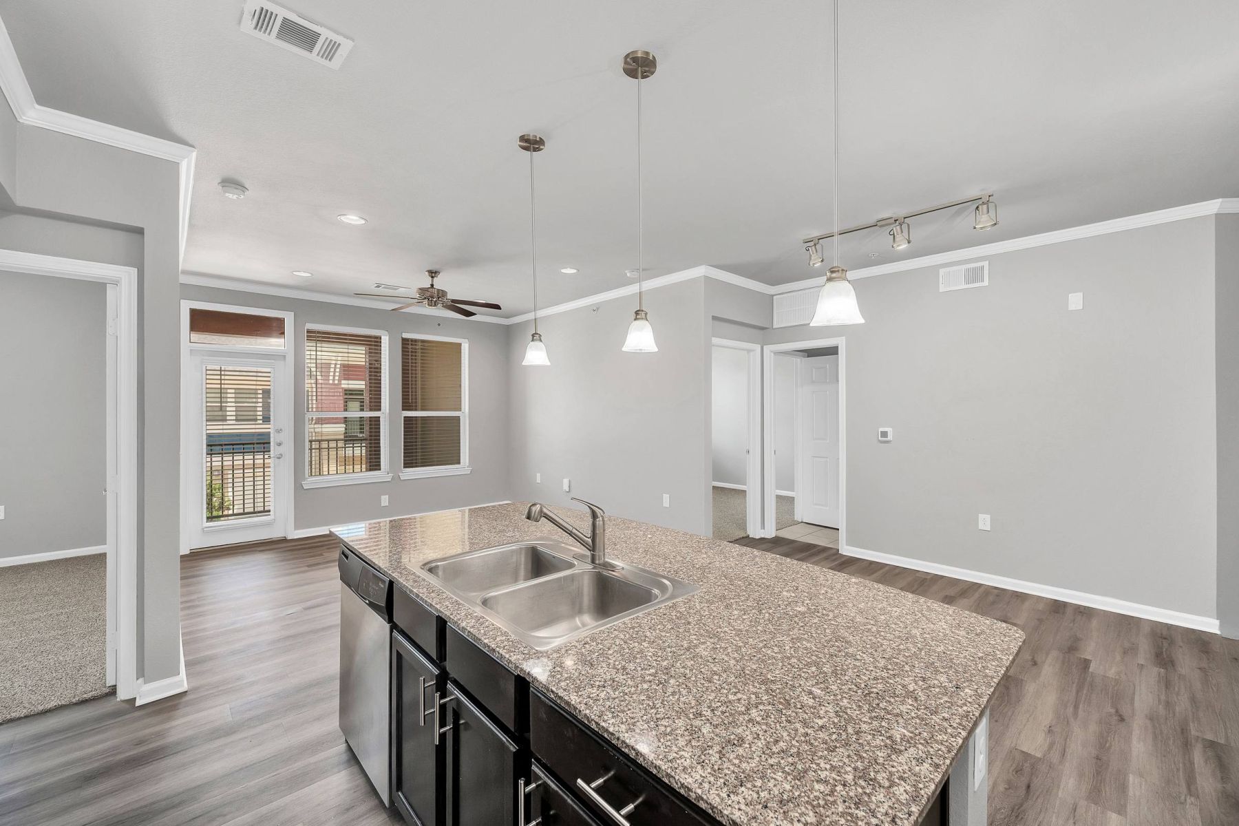 Empty room with wood floors, ceiling fan, and sliding glass door leading to a patio with vertical blinds at Apex West Midown.